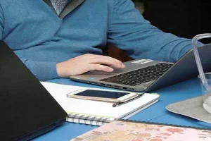 Ilustración de un profesional trabajando desde su domicilio mediante ordenador y conexión digital, representando las modalidades de trabajo a distancia y teletrabajo.